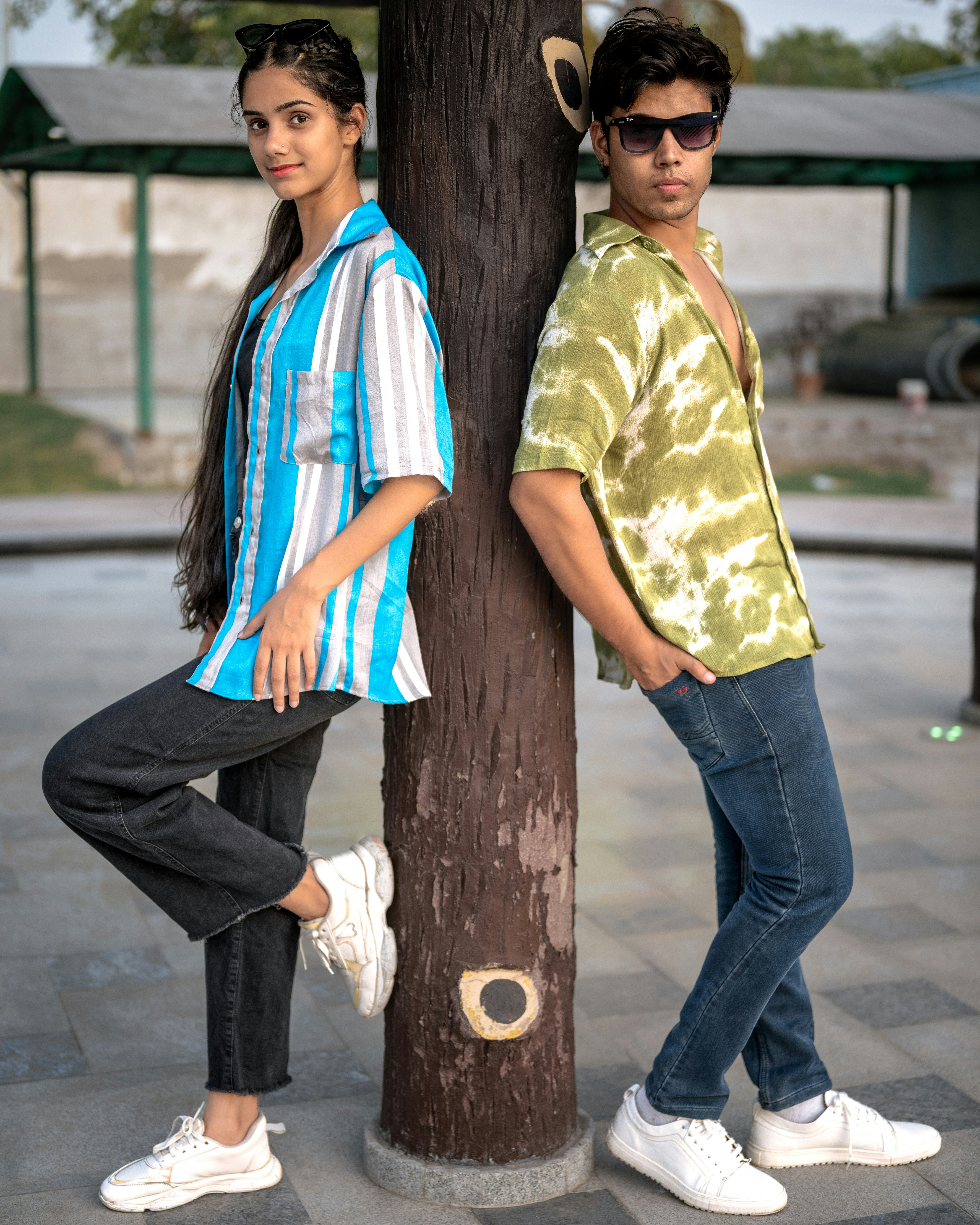 A man and a woman standing next to a tree
