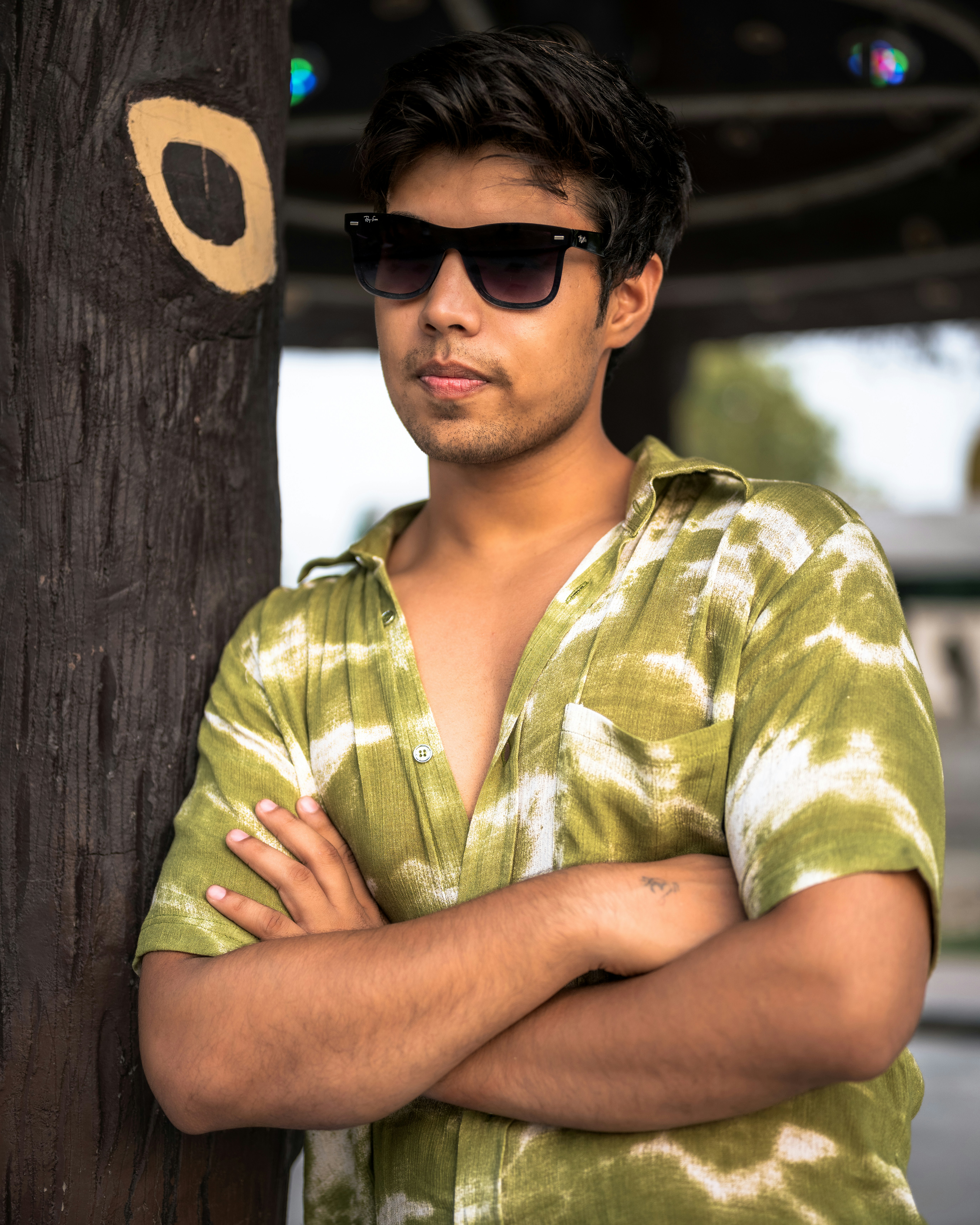 A man with his arms crossed leaning against a pole