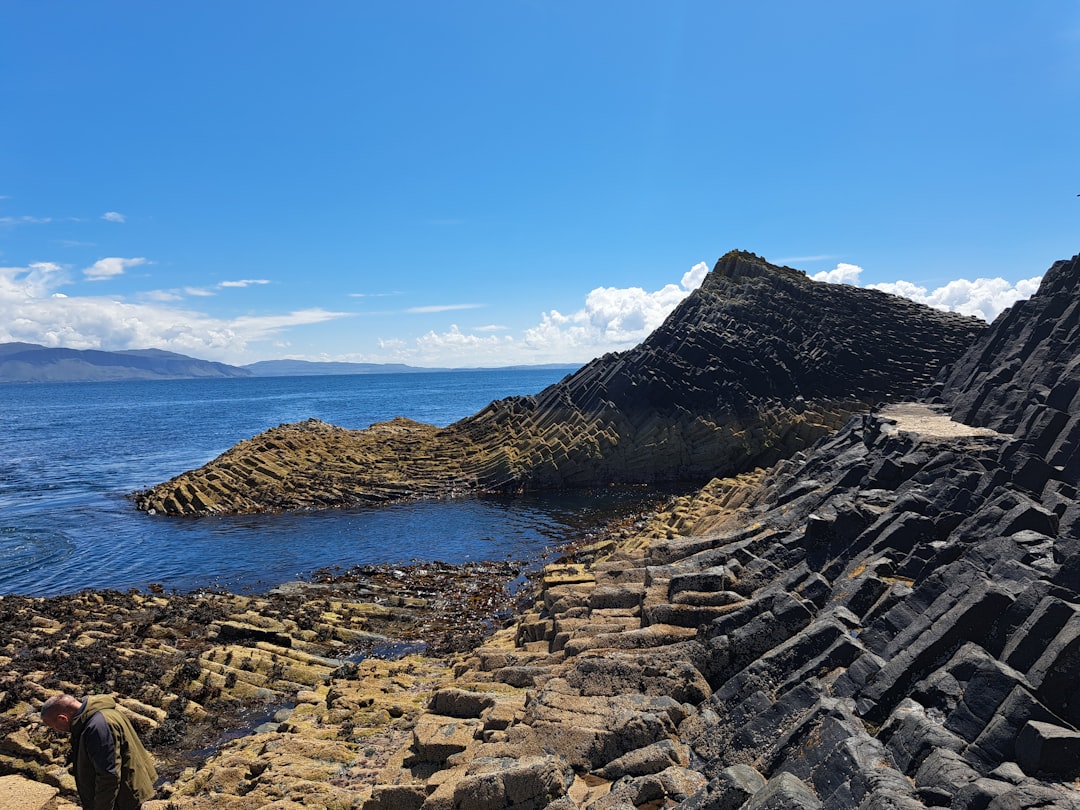 A man standing on top of a rocky beach next to the ocean,