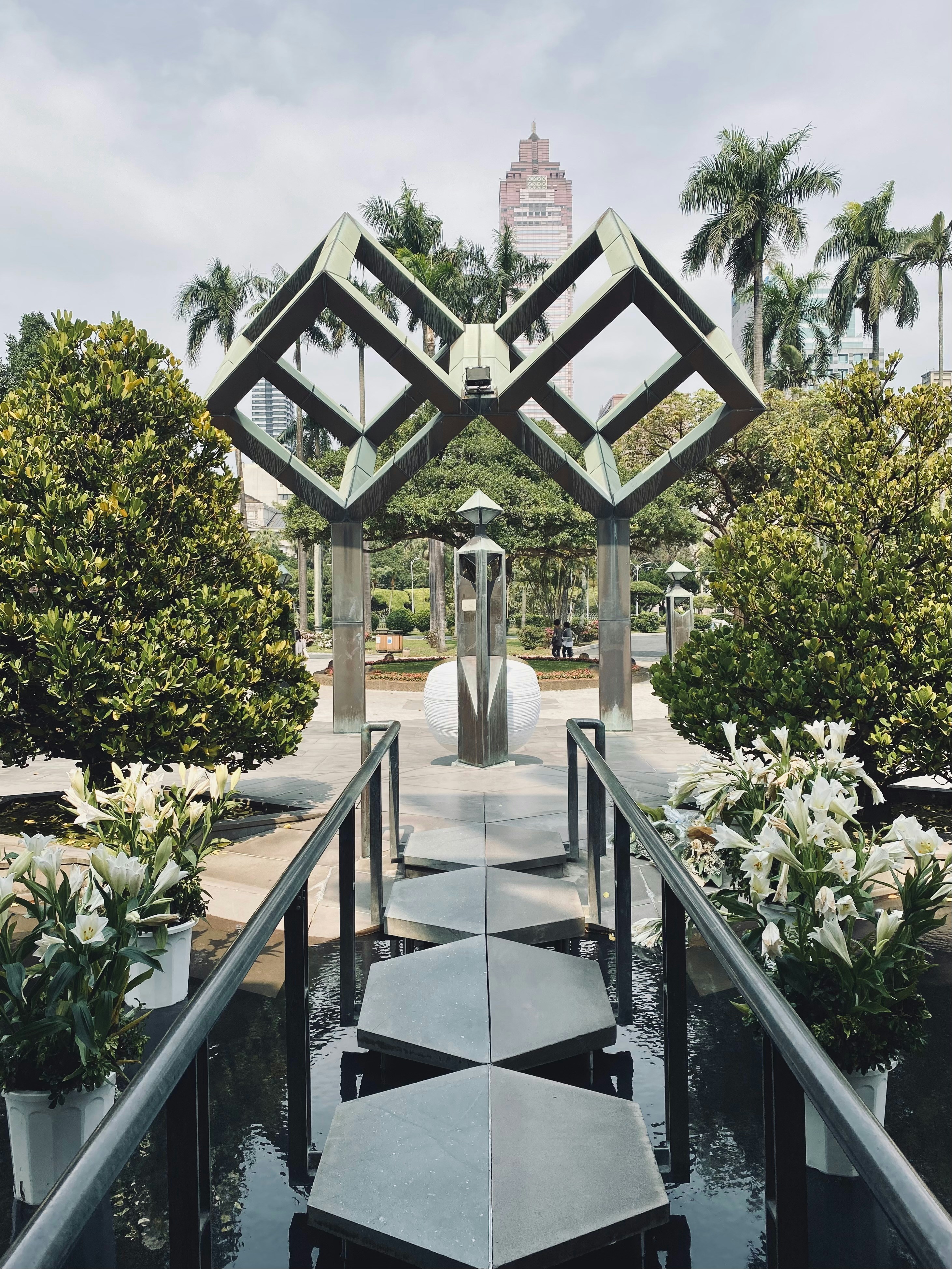 A black and white walkway surrounded by trees and flowers