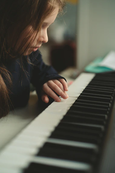 A young girl is playing the piano with her hands