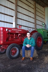 A man sitting on a hay bale next to a tractor