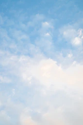 A plane flying high in the sky with clouds