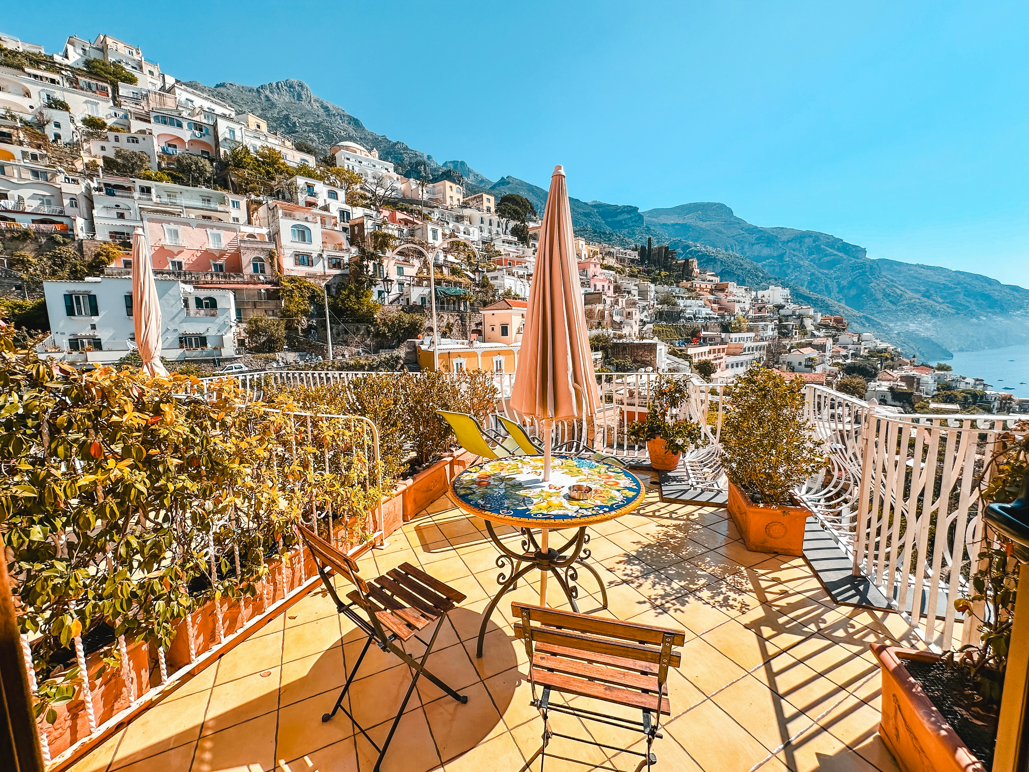 A balcony with a table and chairs and a view of the ocean, 
