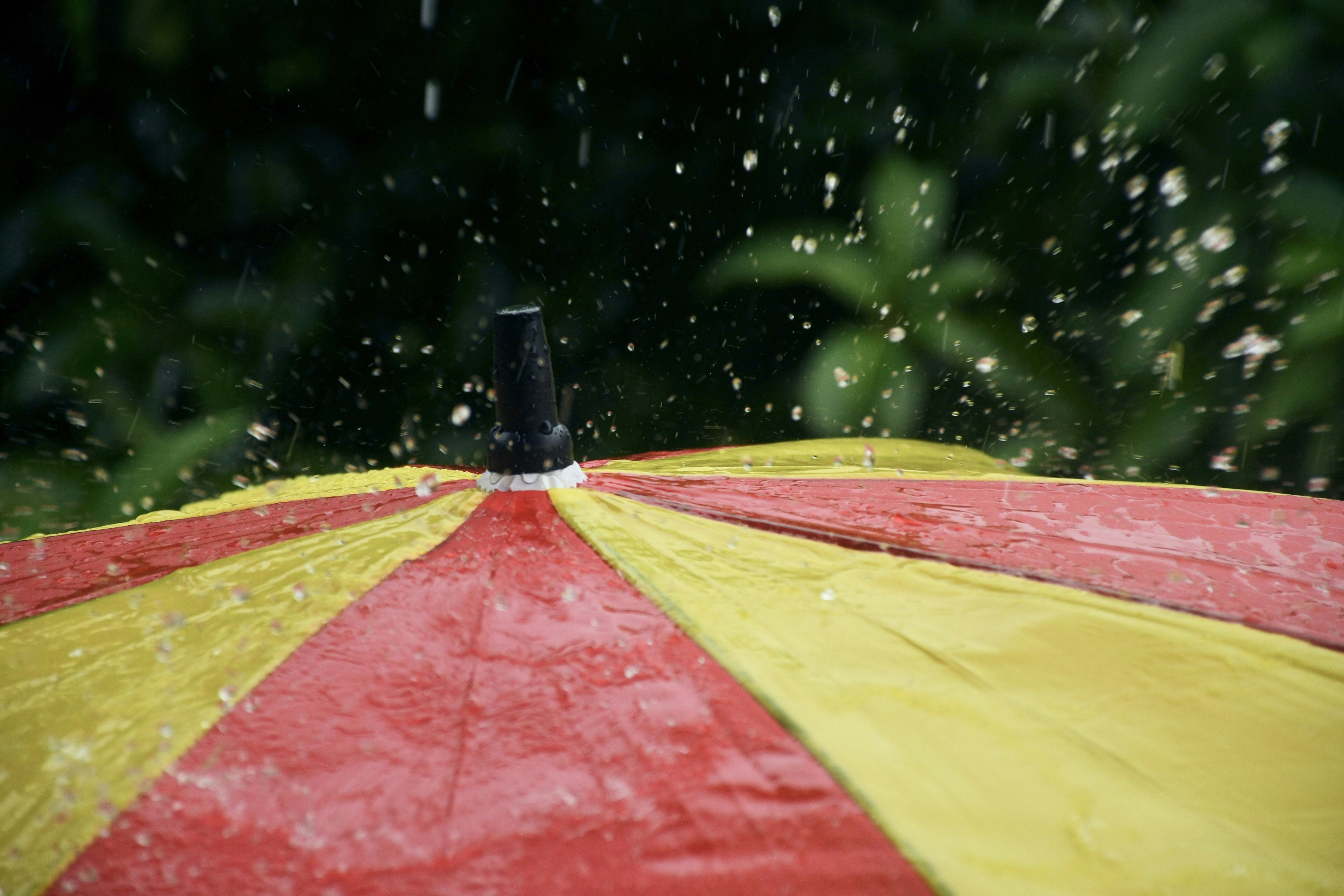A red and yellow umbrella is in the rain
