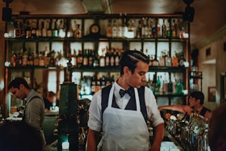 A man in an apron standing in front of a bar