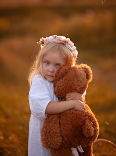 A little girl holding a teddy bear in a field