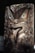 A wooden carving of a face with green eyes