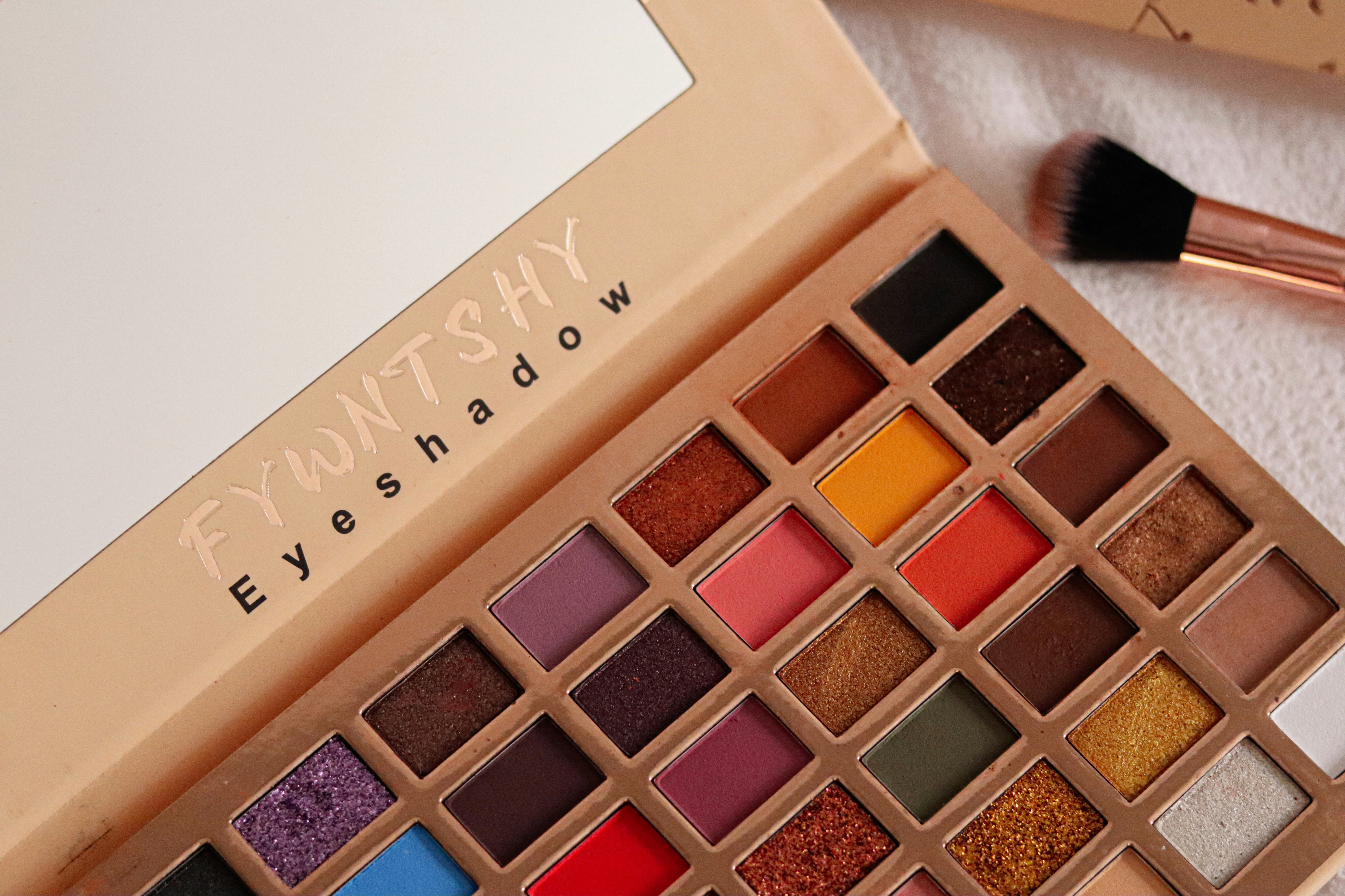 A palette of eyeshades and a brush on a towel