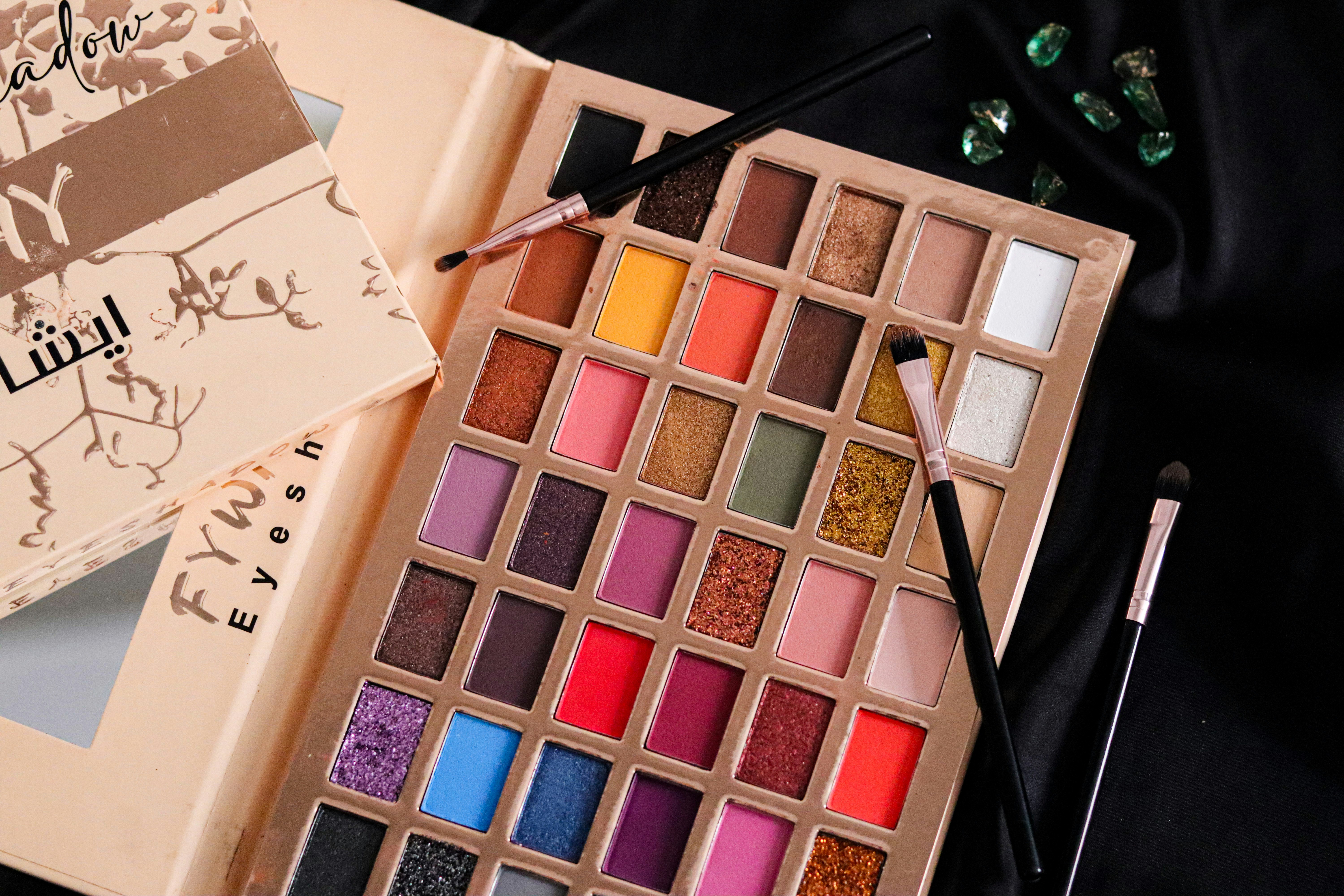 A palette of makeup and a book on a table