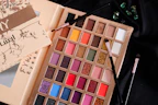 A palette of makeup and a book on a table