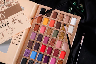 A palette of makeup and a book on a table