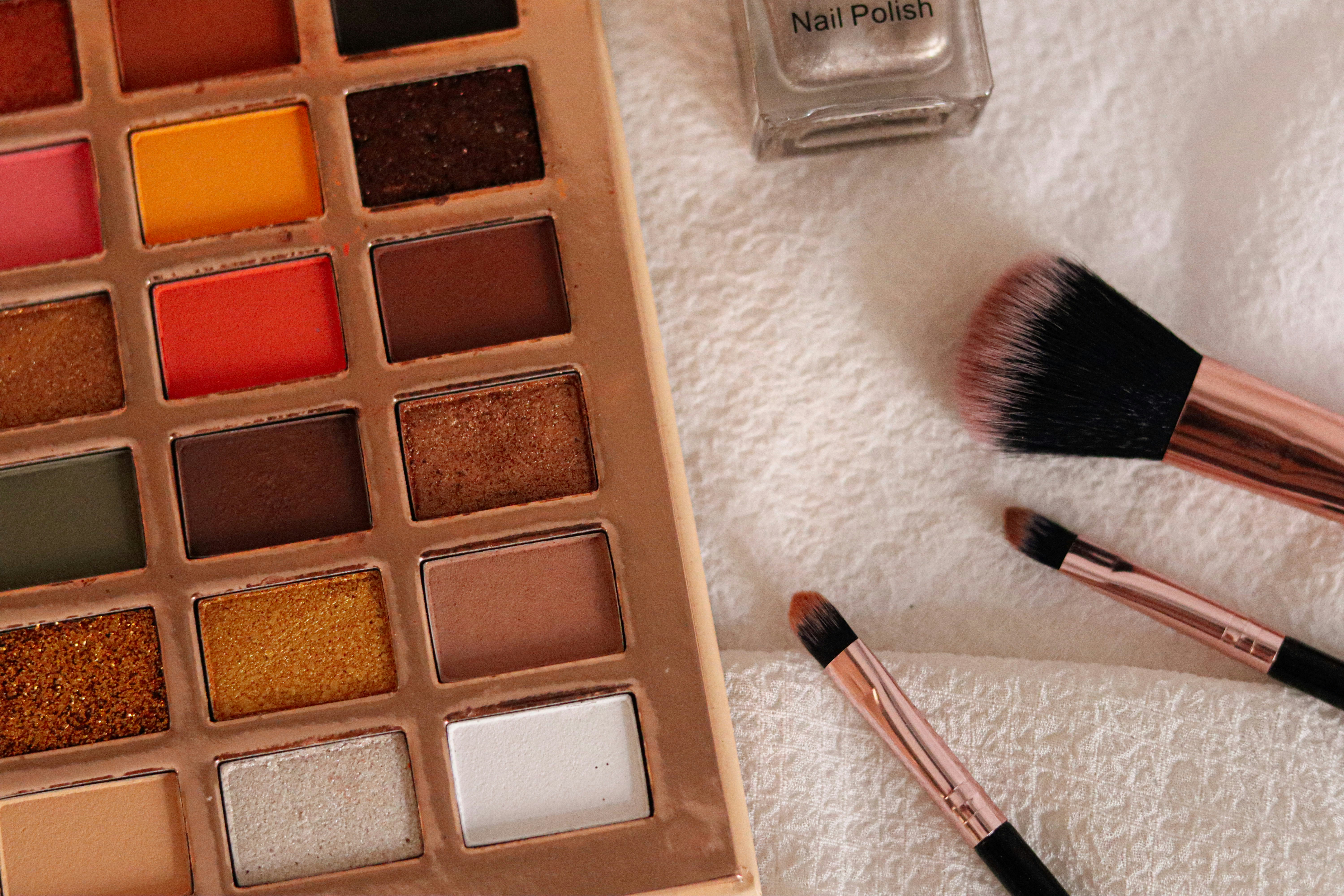 A palette of makeup and a brush on a towel