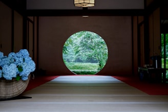 A room with a large circular window and flowers in a basket