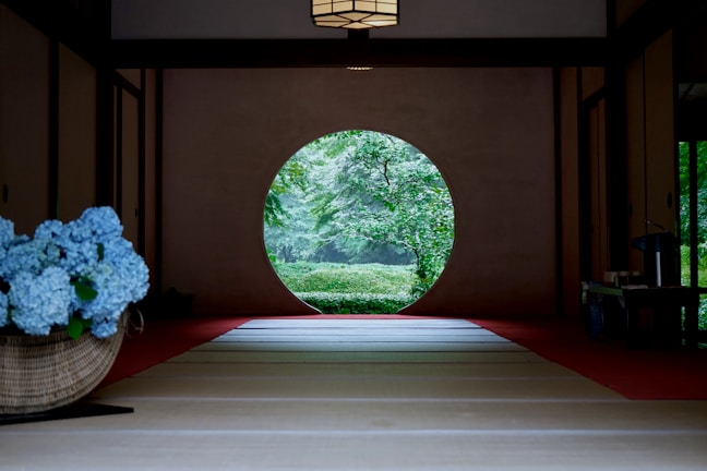 A room with a large circular window and flowers in a basket