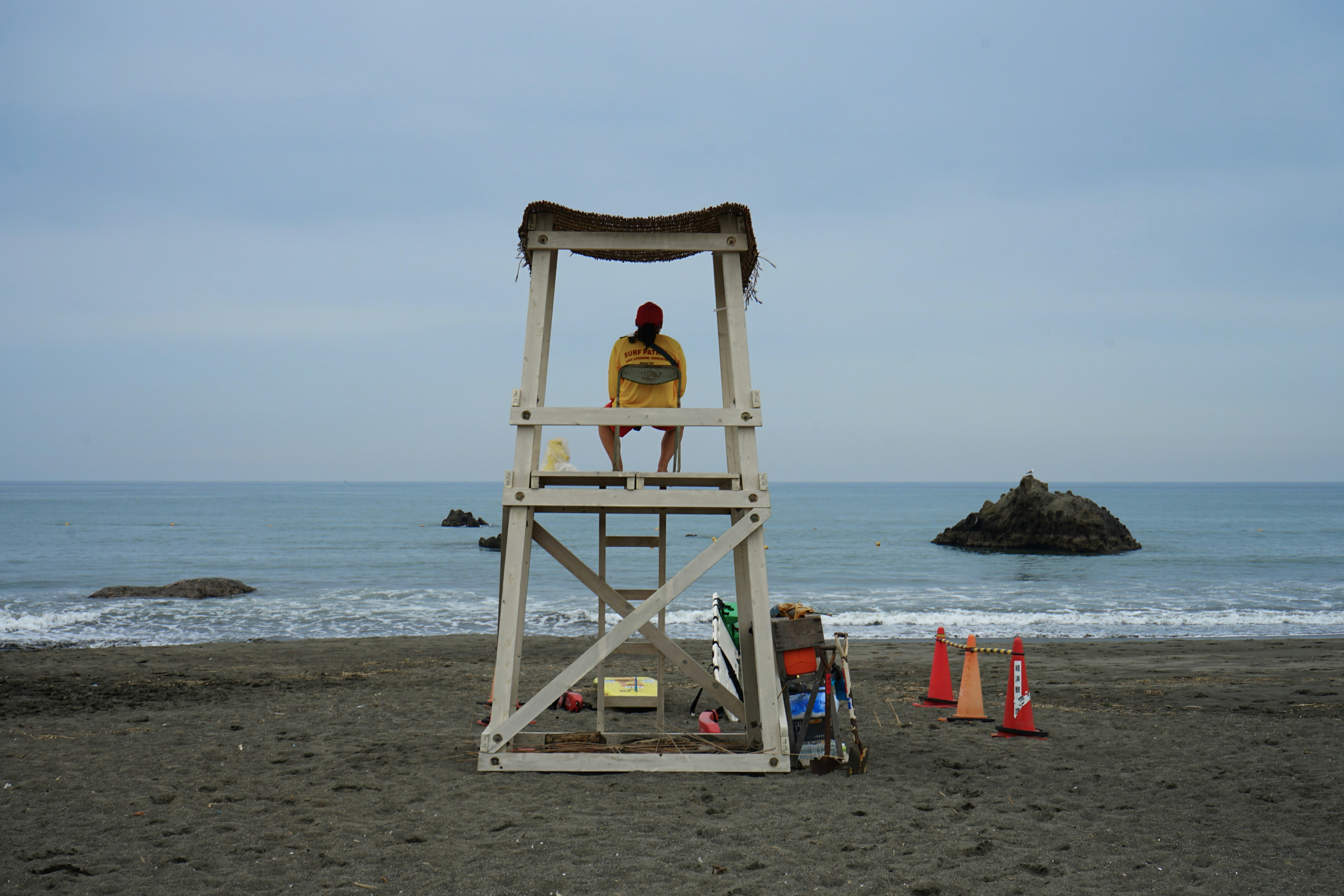 A lifeguard tower on the beach with a man standing on it