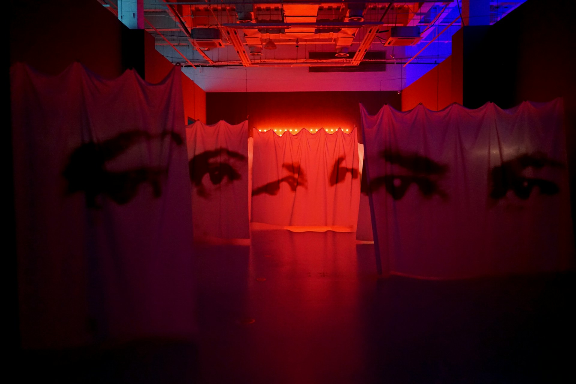A dark room with a red light and two eyes painted on the walls