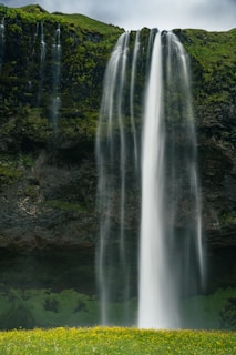 A large waterfall with a man standing in front of it