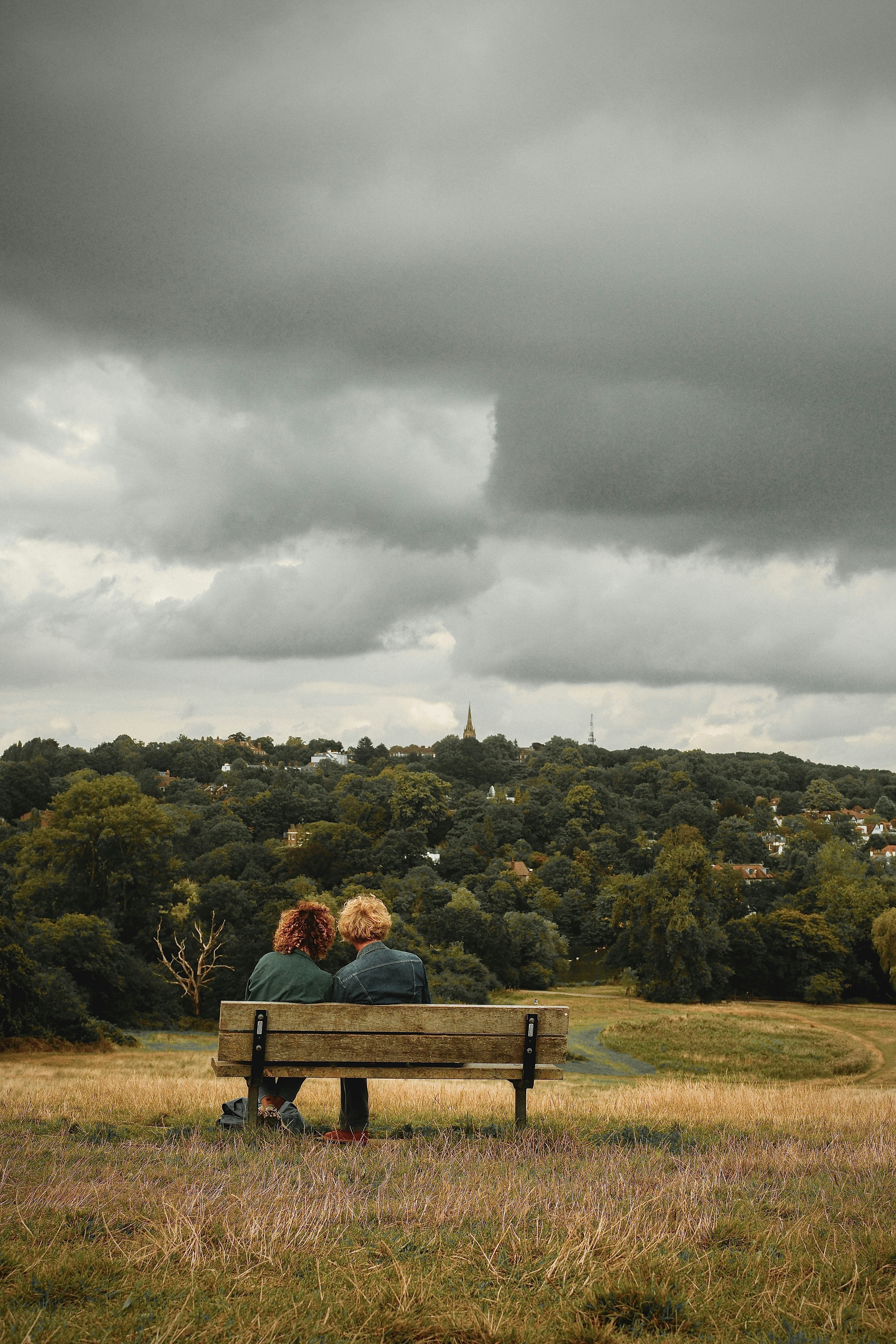 Two people sitting on a bench in a field