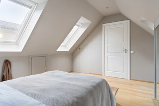 A bedroom with a large bed and a skylight
