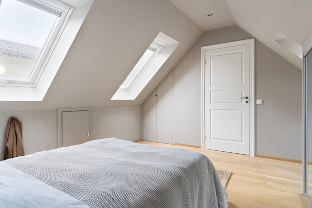 A bedroom with a large bed and a skylight