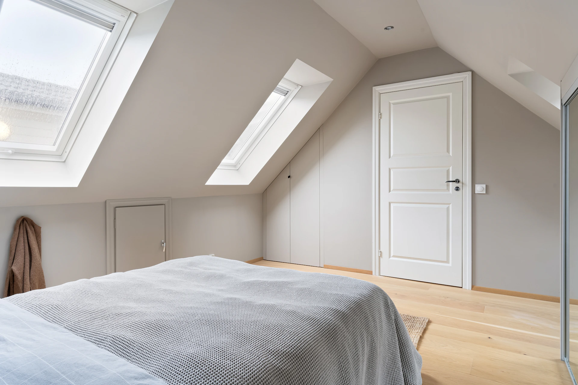 A bedroom with a large bed and a skylight
