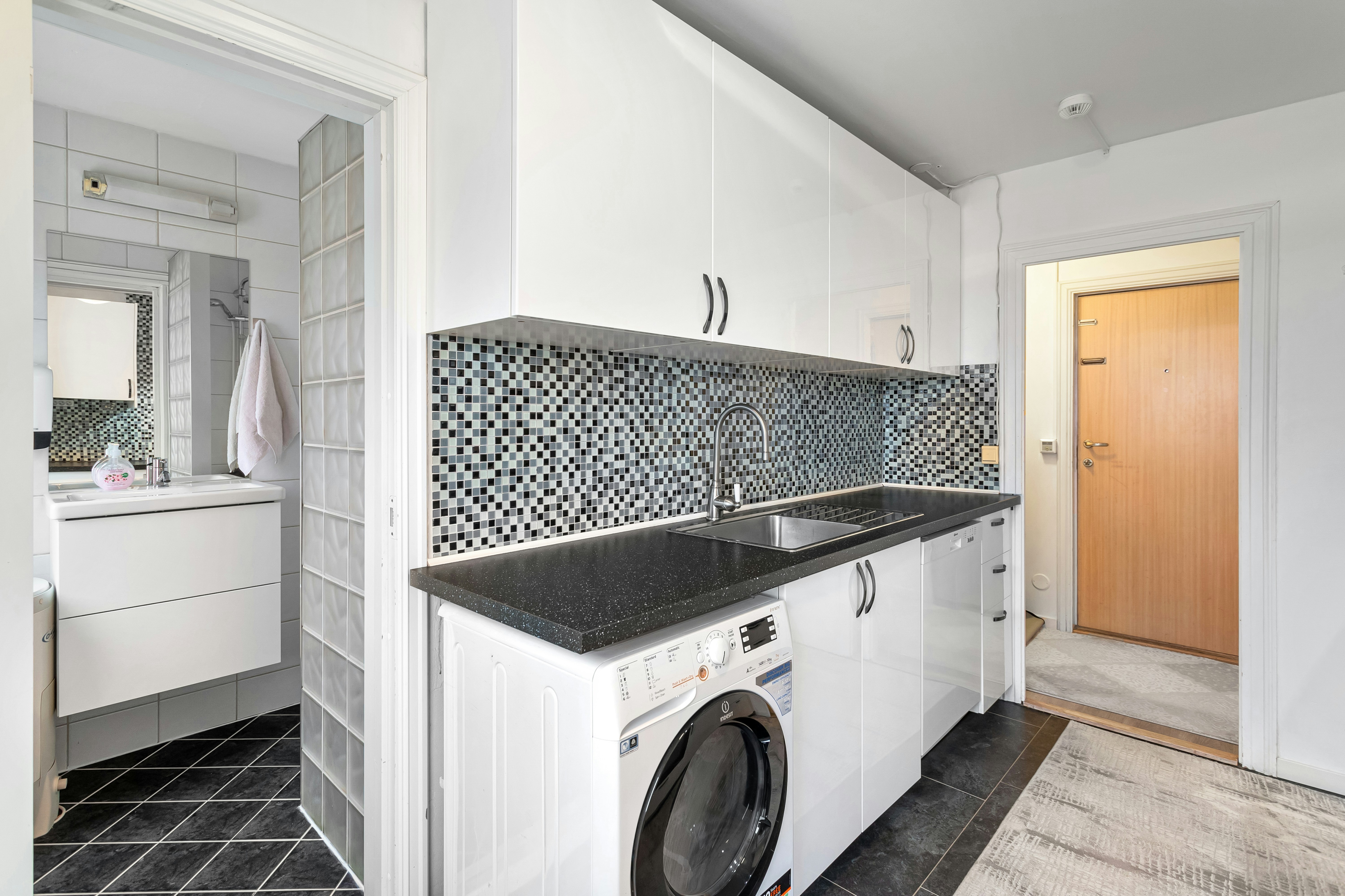 Modern kitchen with stainless steel refrigerator and washing machine in bright white setting