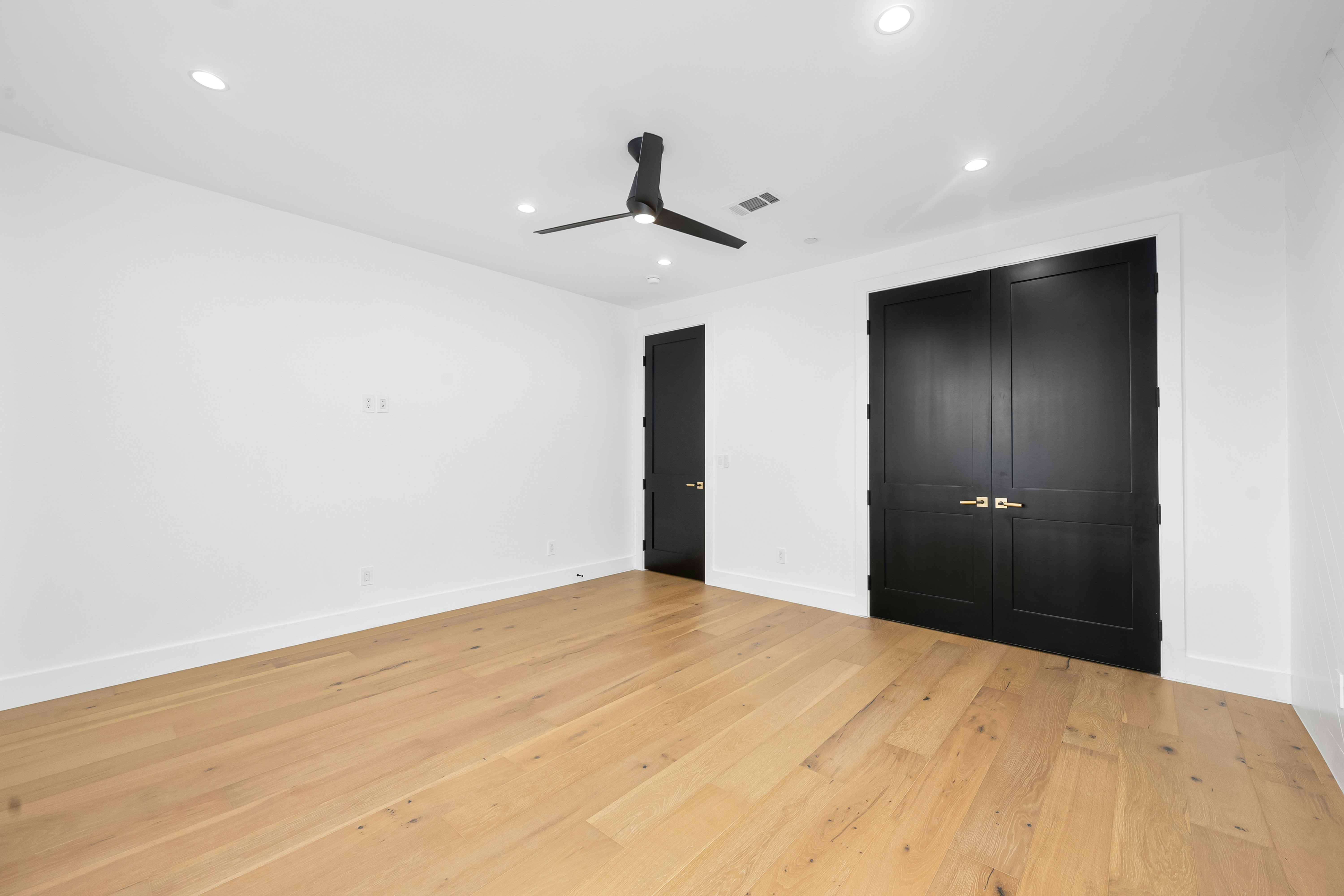 Empty room with black doors and ceiling fan