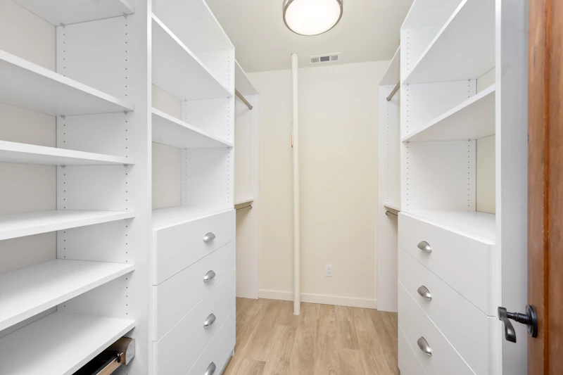 Walk-in wardrobe with white shelves and pull-out drawers