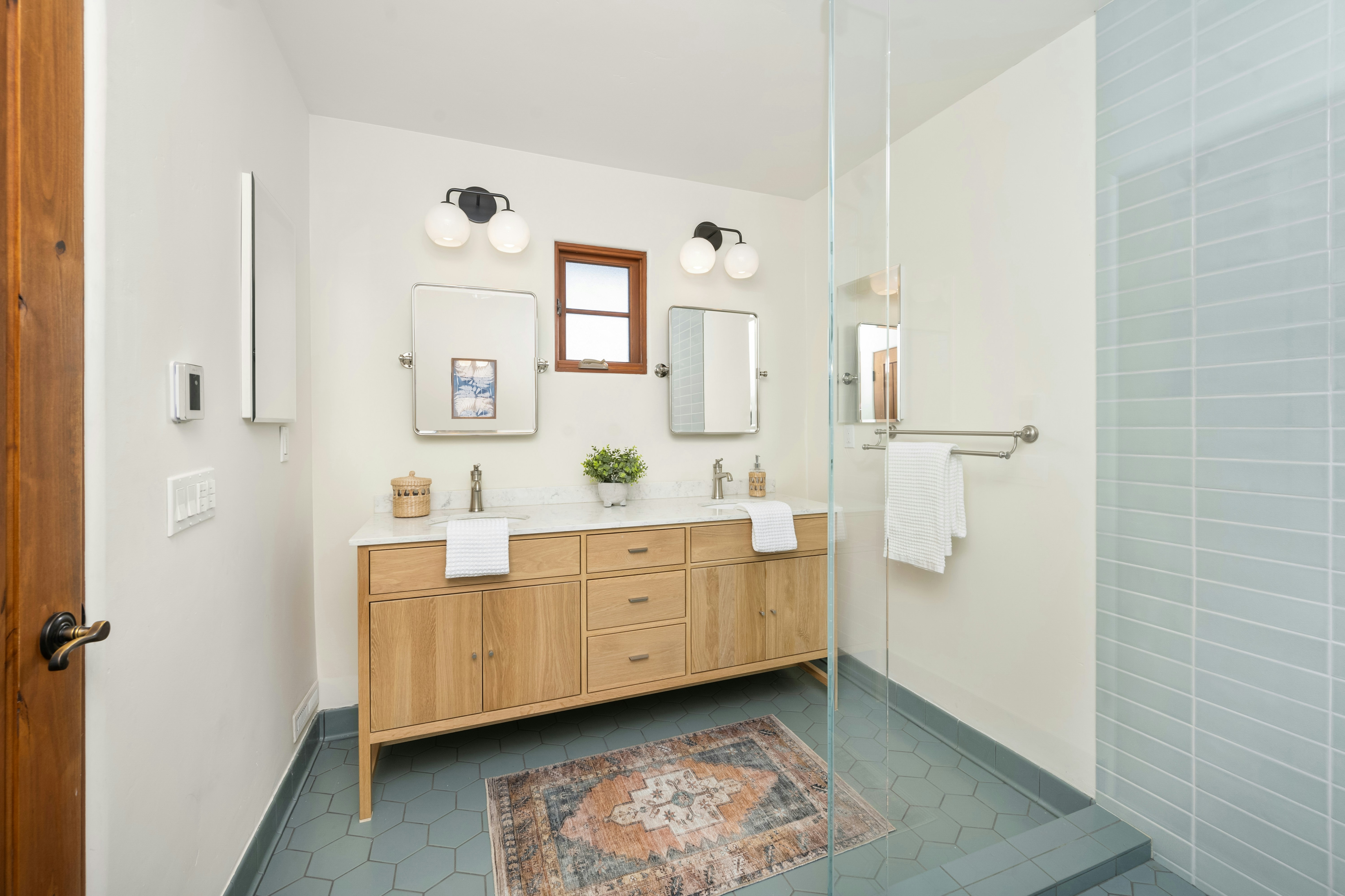 A bathroom with a sink, mirror, and shower stall