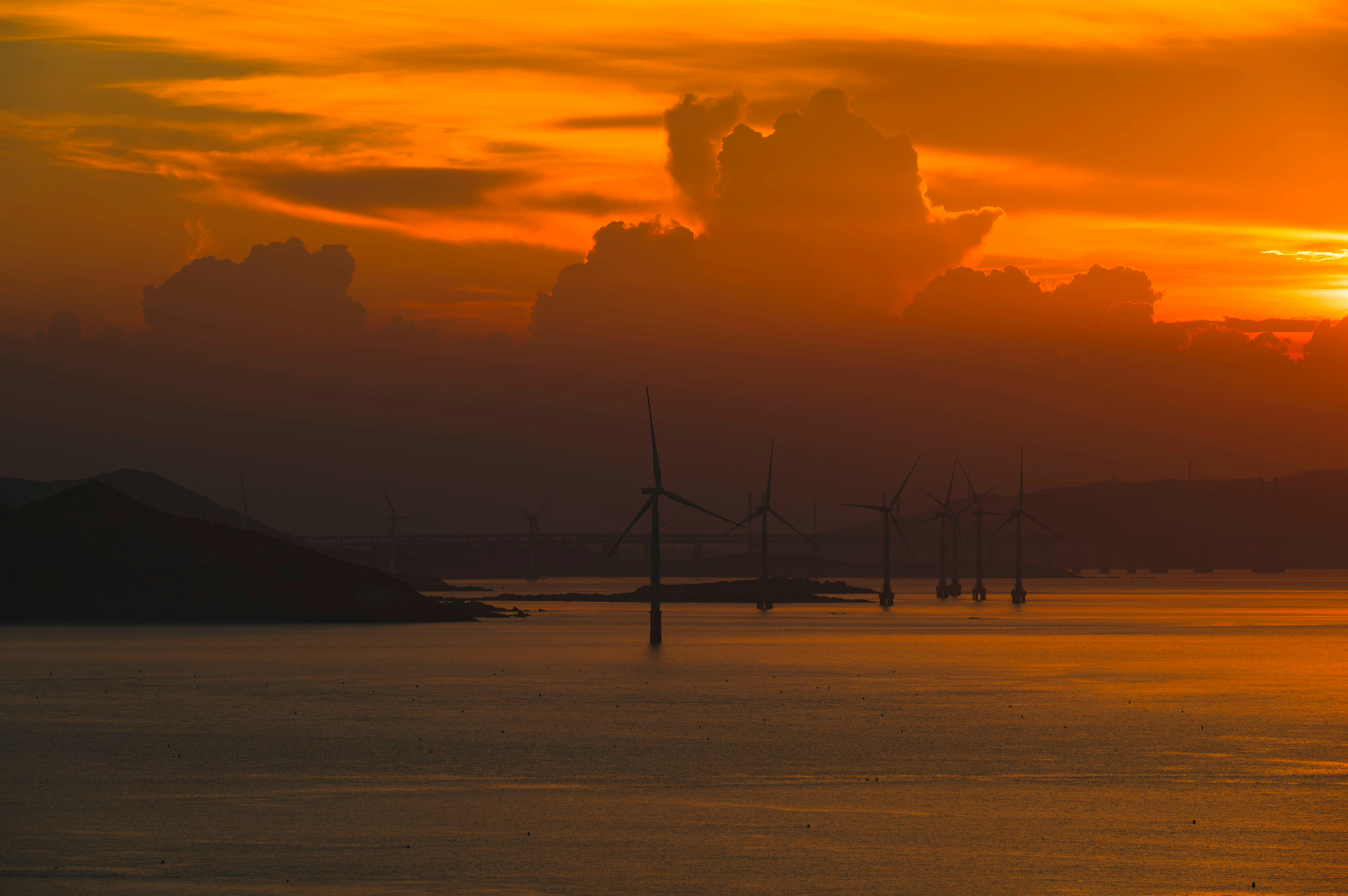 Aerial view of offshore wind turbines in the sea at golden hour with dramatic sky