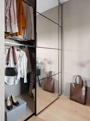 A walk in closet with a mirror and a purse