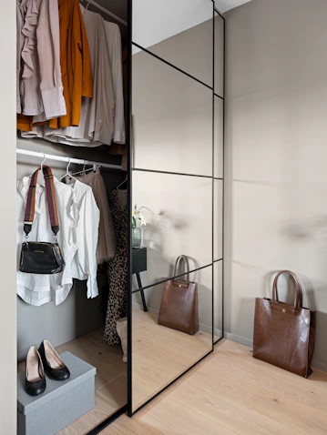 A walk in closet with a mirror and a purse