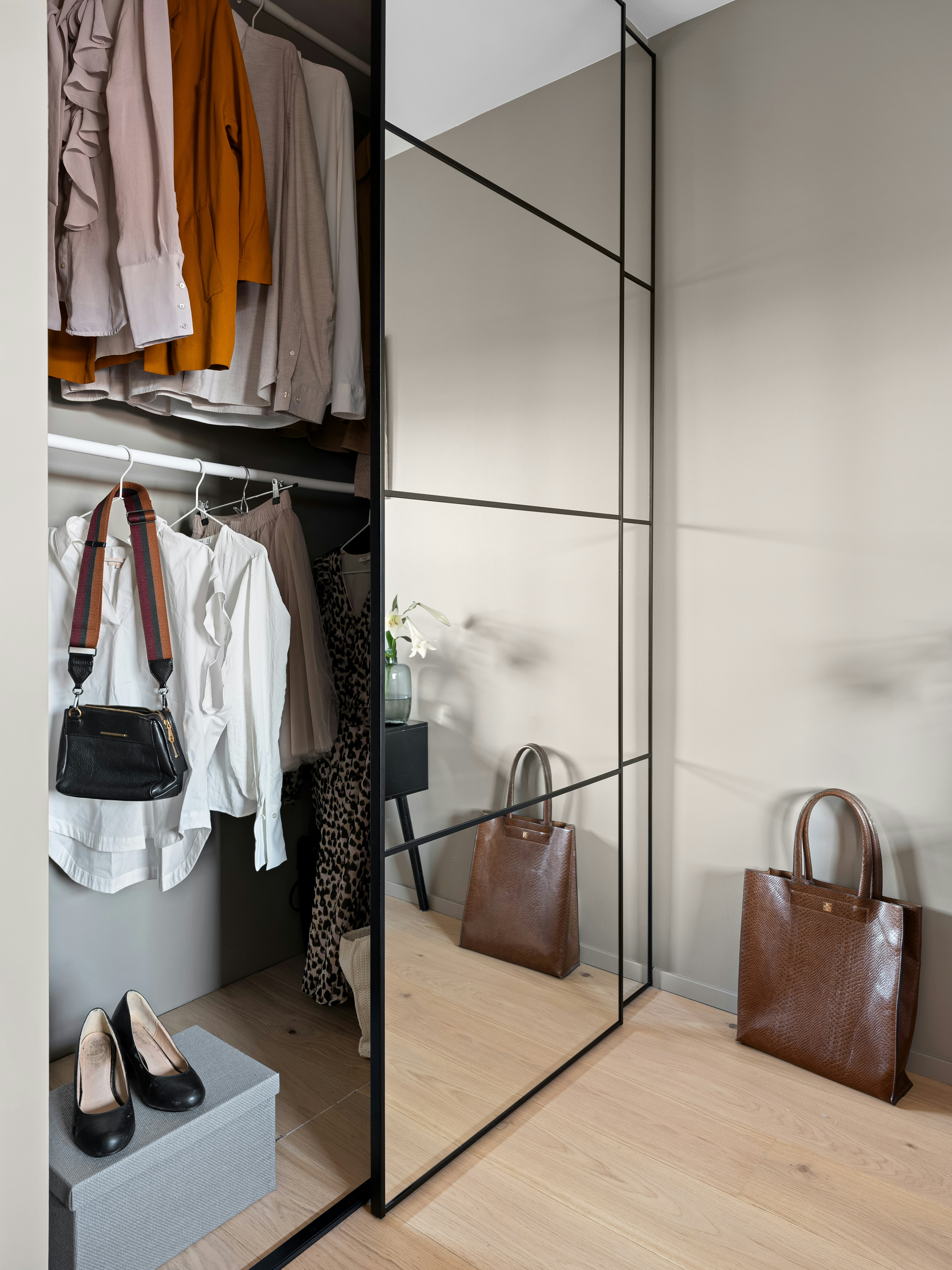 A walk in closet with a mirror and a purse