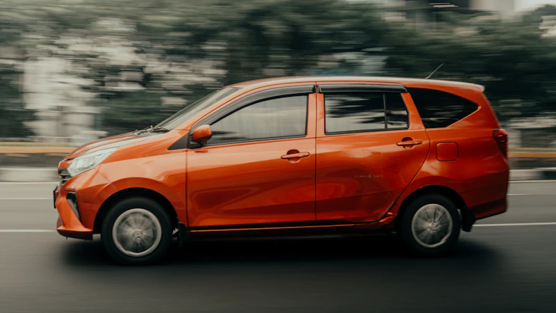 Small orange car driving down a street