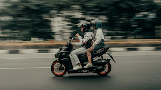 Two people riding a motorcycle on a city street