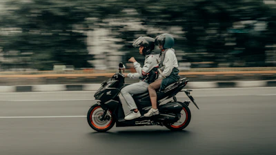 Two people riding a motorcycle on a city street