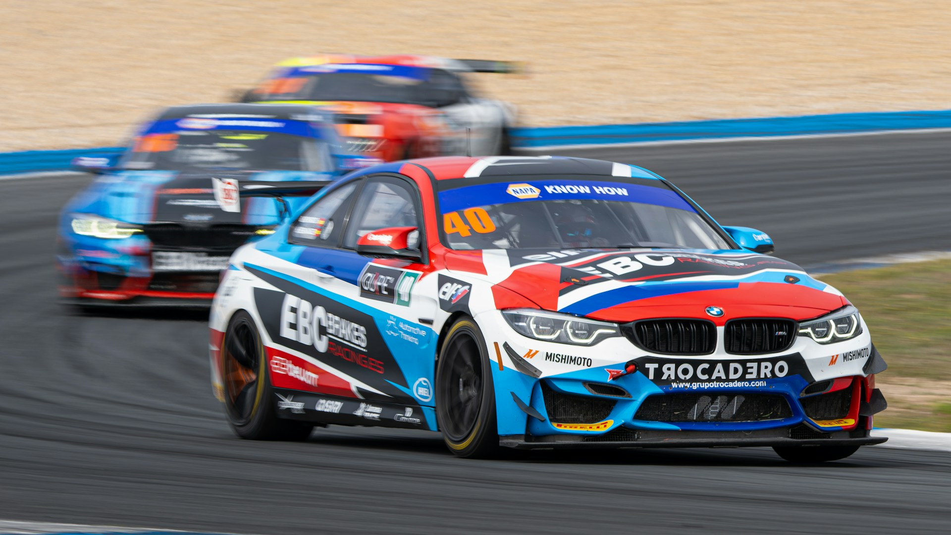 A couple of cars driving down a race track