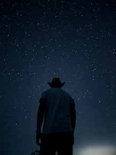 A man in a cowboy hat looking at the stars