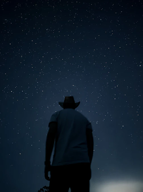 A man in a cowboy hat looking at the stars