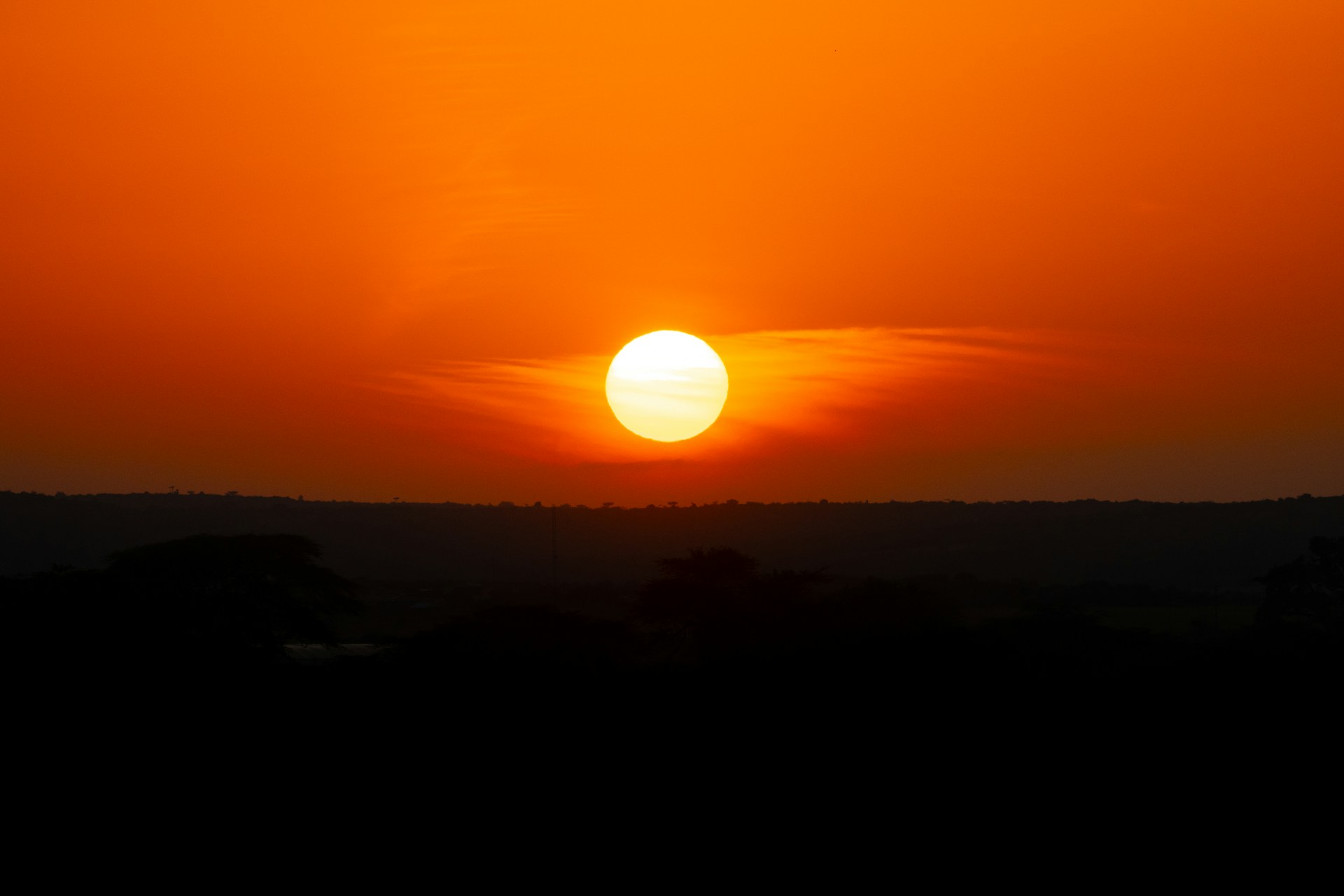 The sun is setting over the horizon of a field
