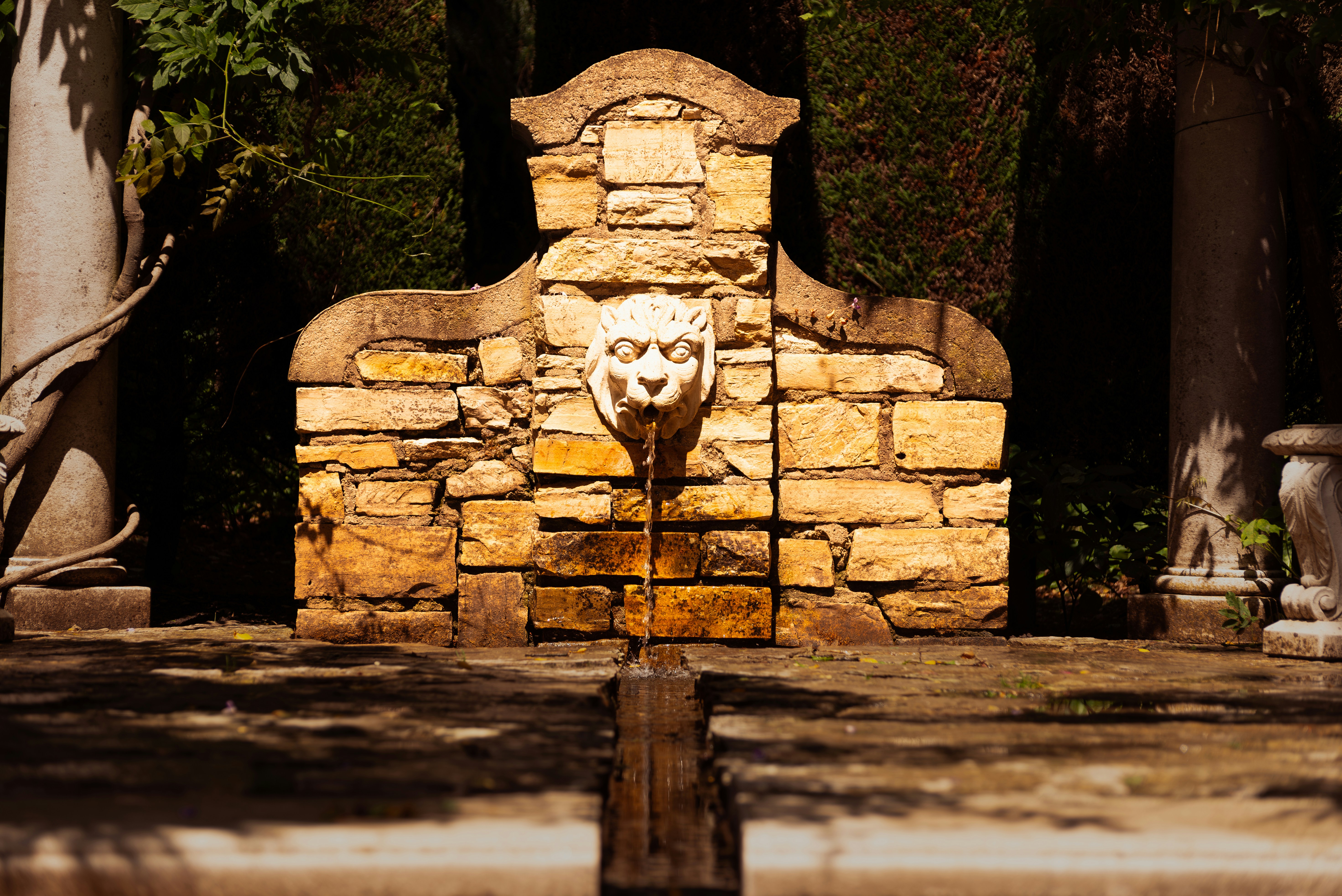 A stone fountain with a lion head on it