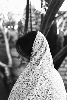A black and white photo of a woman sitting on a bench