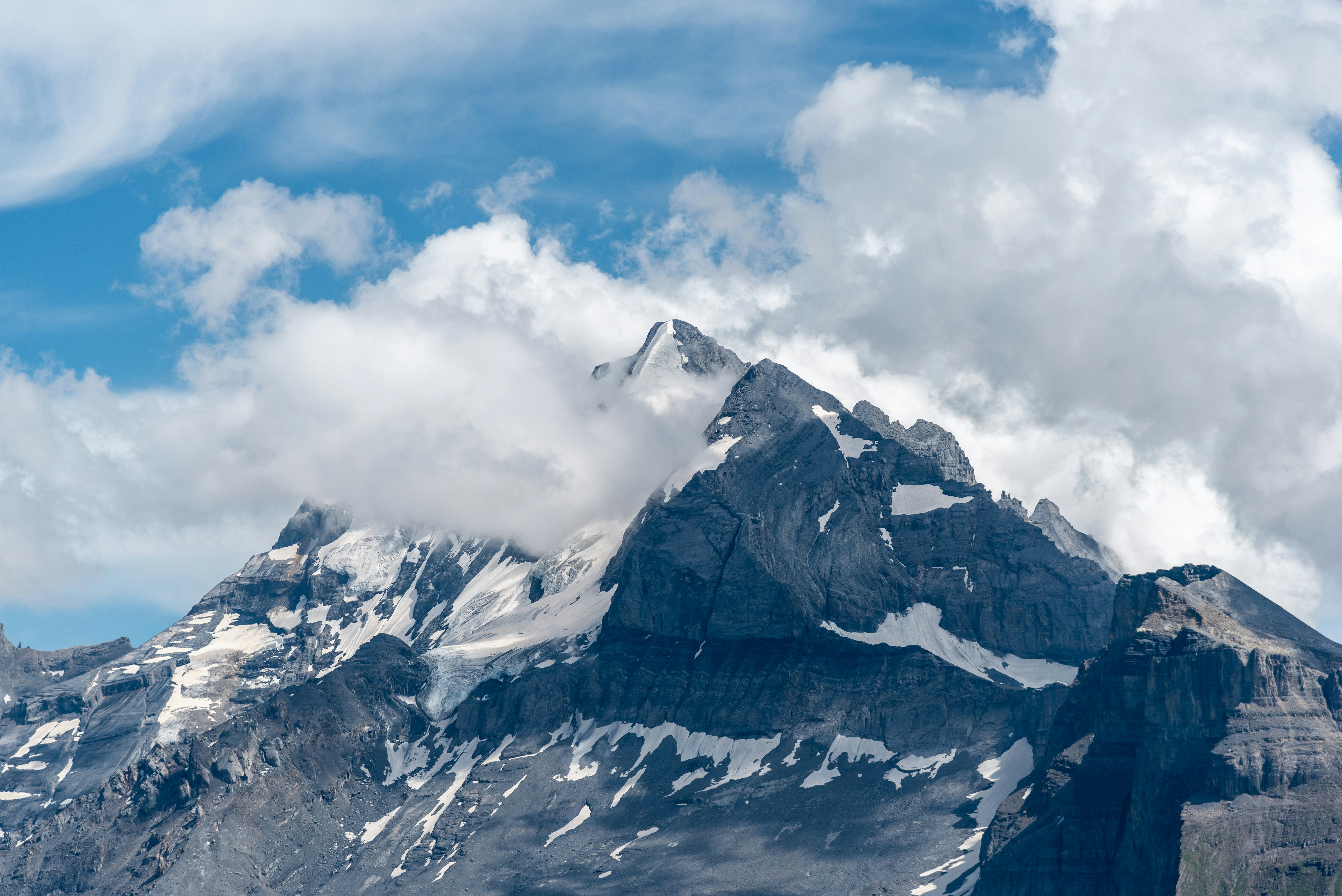 A mountain with snow on the top and clouds in the sky