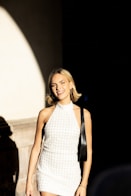 A woman in a white dress is walking down the street