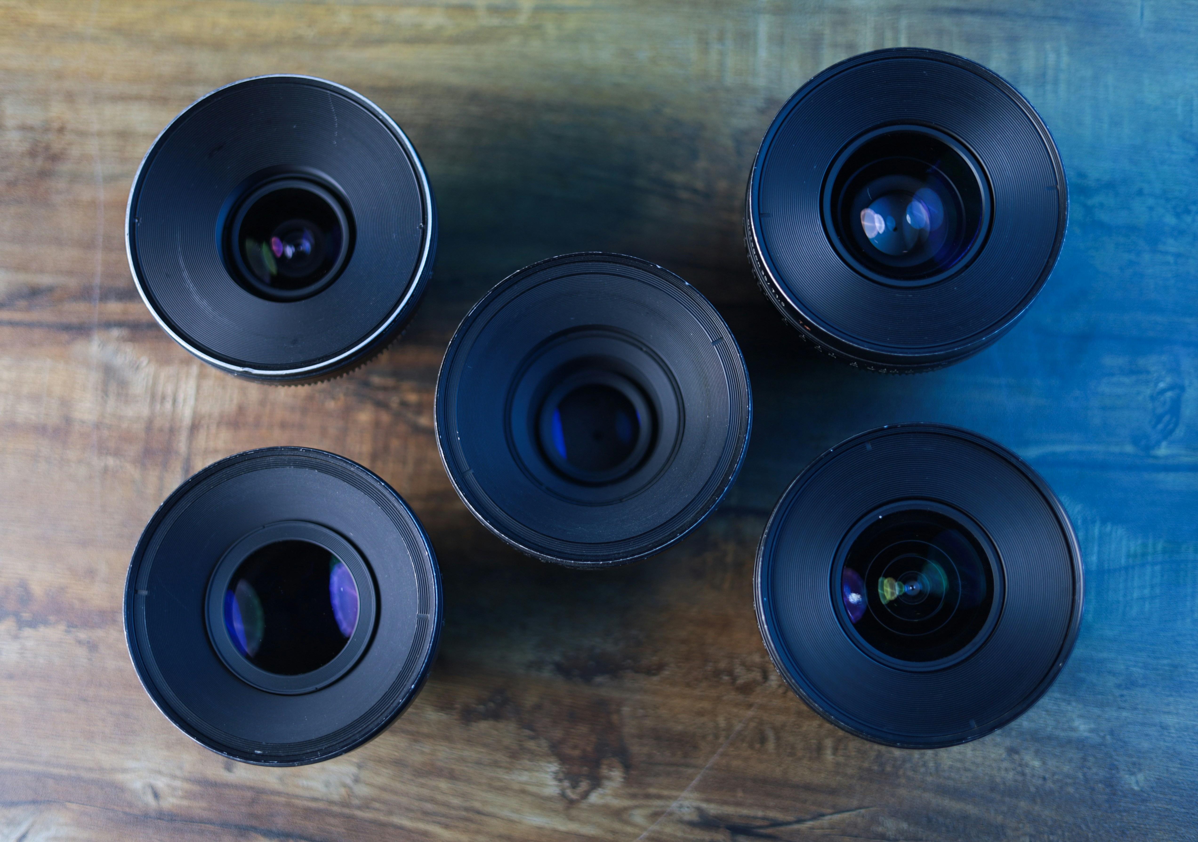 A group of four cameras sitting on top of a wooden table