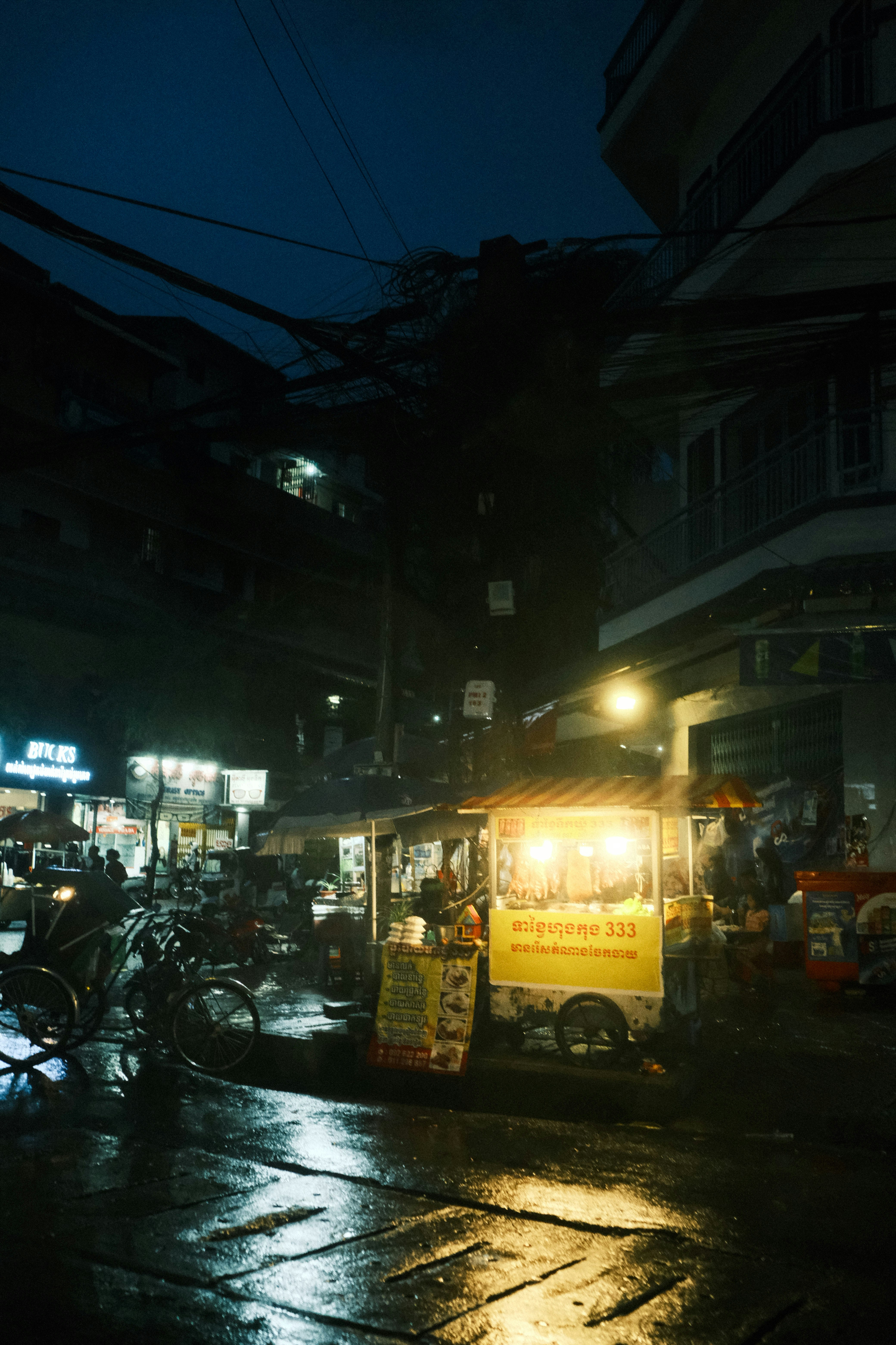 A food truck parked on a wet street at night