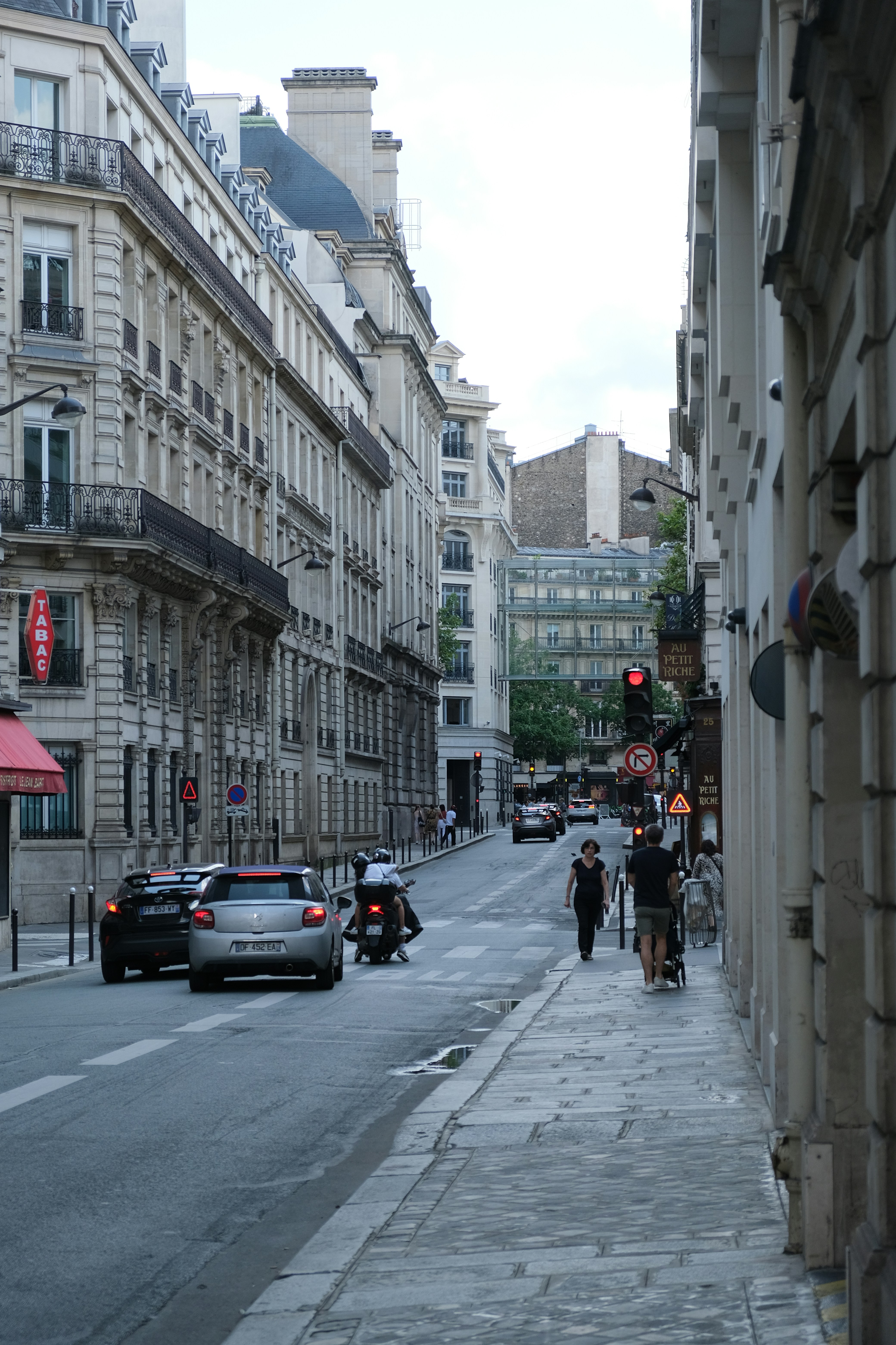A couple of people walking down a street next to tall buildings