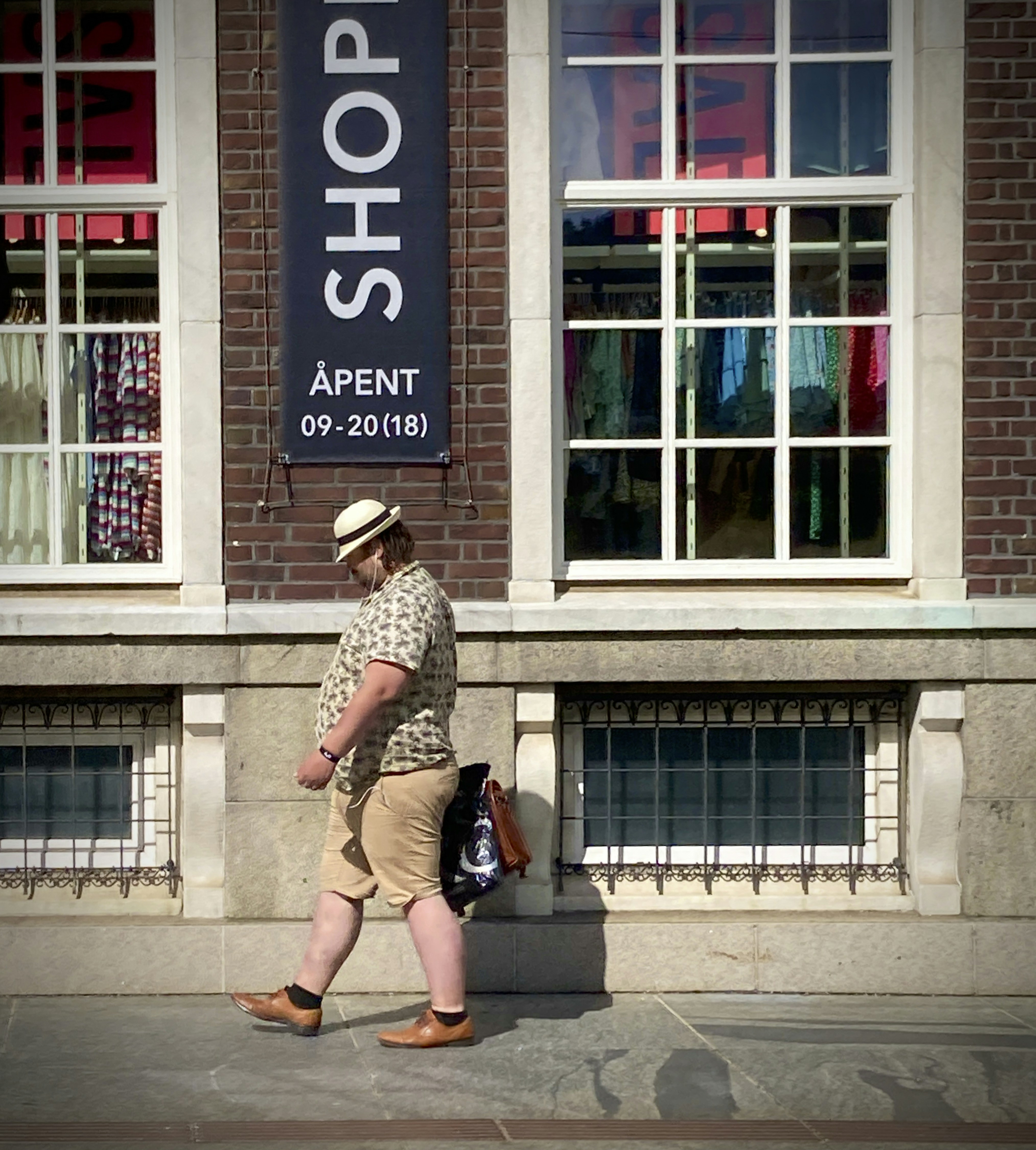 A man walking down the street in front of a store