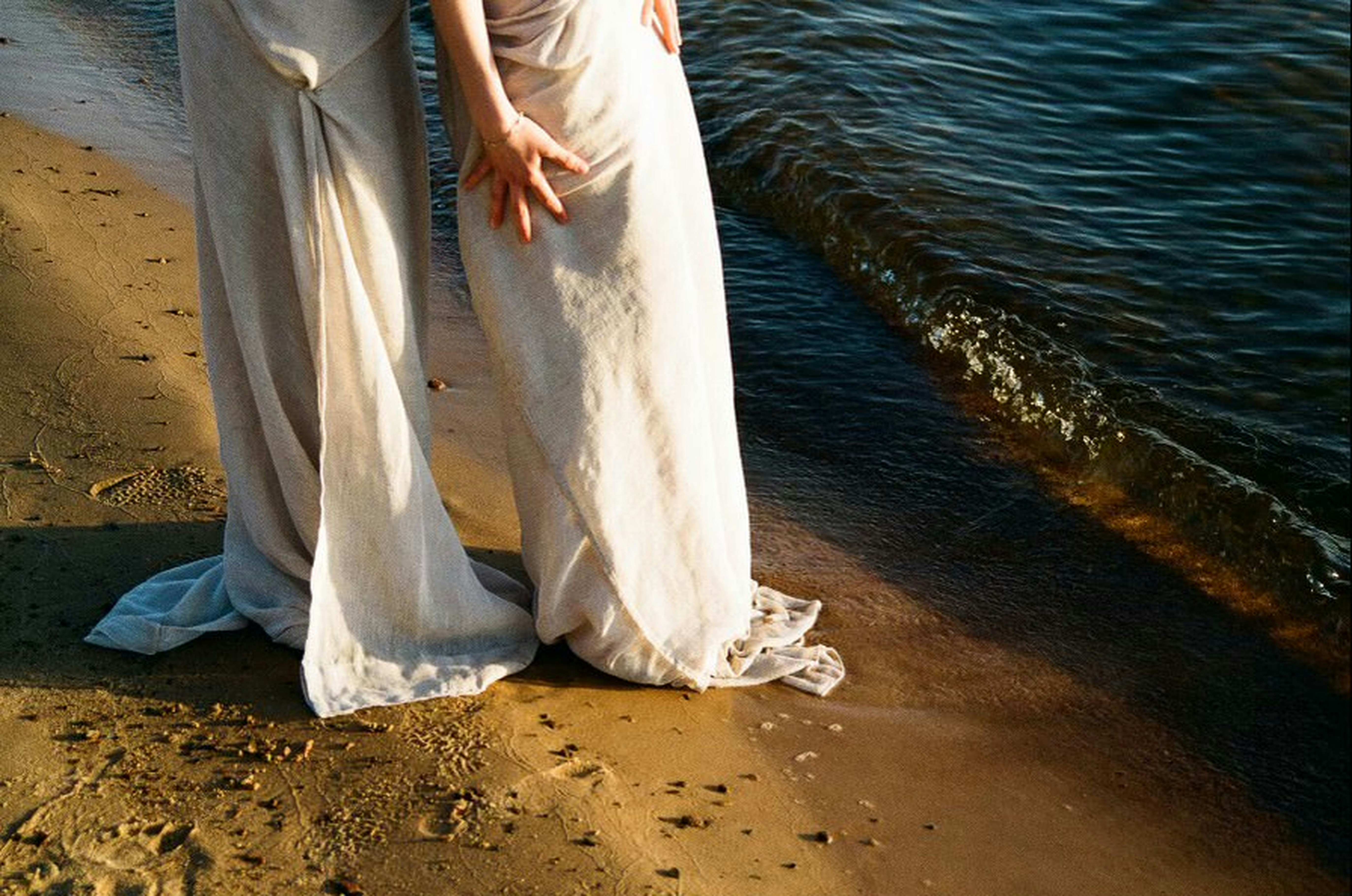 A man and a woman standing on a beach next to the ocean